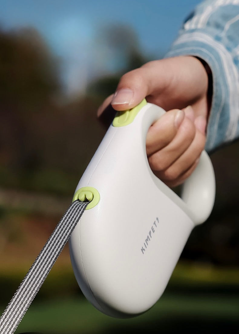 Hand holding a white and green device with a blurred outdoor background
