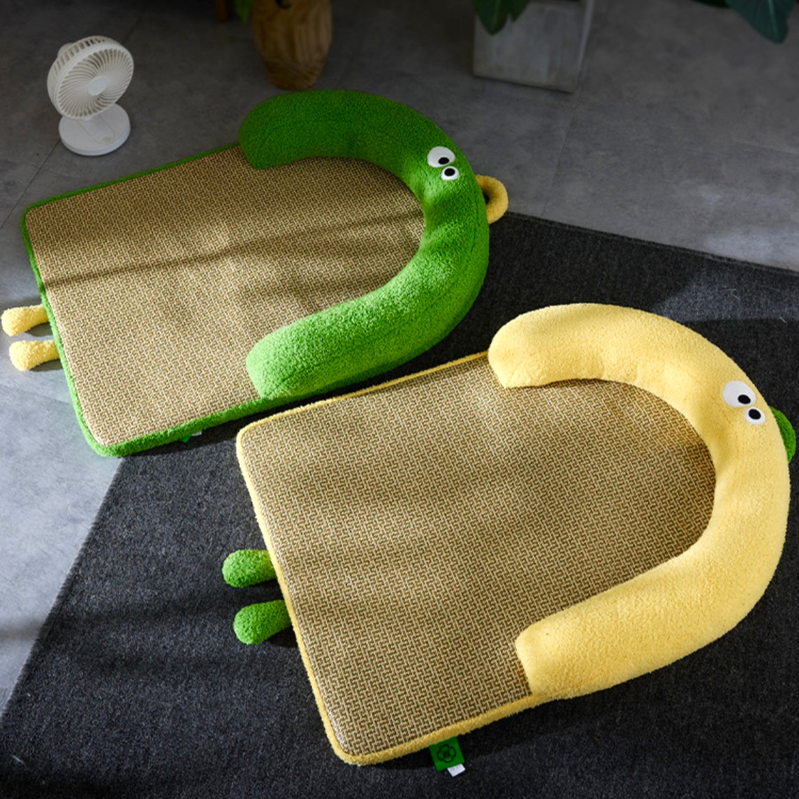 Two green and beige pet beds shaped like lizards on a dark rug.